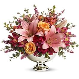 Pink lilies and roses arranged in a silver pedestal vase
