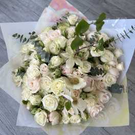 Bouquet of white and blush roses with greenery in pastel wrapping