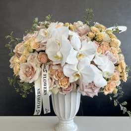 Bouquet of pale roses and white orchids in a white vase
