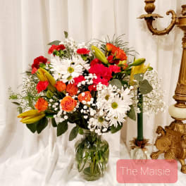 Mixed bouquet of daisies, roses, lilies, and carnations in a glass vase