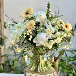 Bouquet of pale yellow and white flowers in a clear glass vase