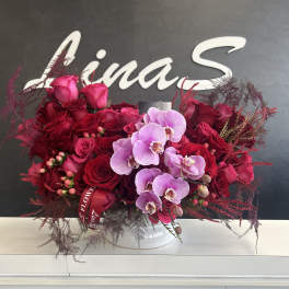 Red rose and pink orchid arrangement in a white vase