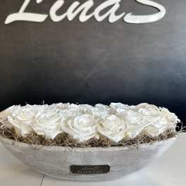 White roses arranged in a shallow gray bowl with dried filler