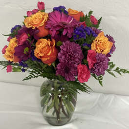 Mixed bouquet of purple, pink, and orange flowers in a glass vase