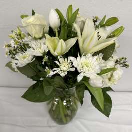 White lilies and daisies arranged in a clear glass vase