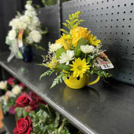 Yellow and white flower arrangement in a smiley-face mug