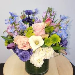 Mixed bouquet in a dark green vase with pink, purple, white, and blue flowers
