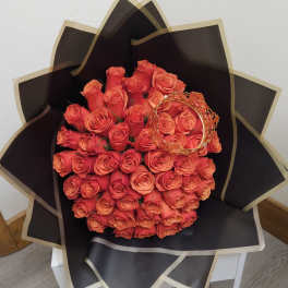 Bouquet of orange roses wrapped in black paper with gold trim
