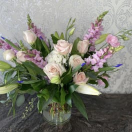 Pink roses and lilies arranged in a glass vase