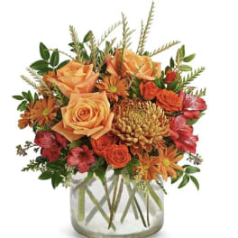 Orange and red mixed flower arrangement in a clear glass vase