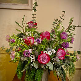 Garden-style arrangement of pink roses and purple anemones in a tall metal vase