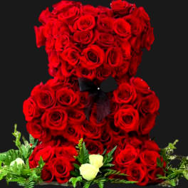 Red rose teddy bear with a black ribbon and small white roses at the base