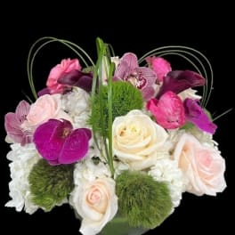 Mixed pink, white, and purple flowers in a glass vase