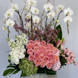 Pink roses and white orchids arranged in a wooden box