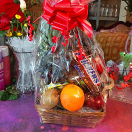 Gift basket with fruit and candy wrapped in clear cellophane and a red bow