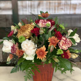 Mixed bouquet of chrysanthemums and carnations in a wooden vase