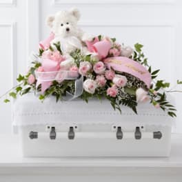 Pink rose arrangement with a teddy bear in a white casket