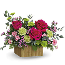 Pink roses and carnations in a wooden box with green filler flowers