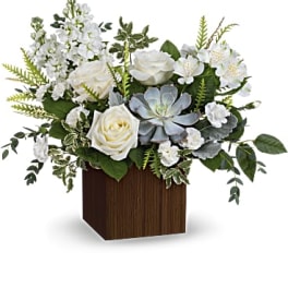 White roses and pale blue succulents in a wooden cube vase