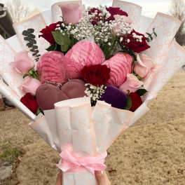 Bouquet of pink and red roses with baby’s breath and heart-shaped gifts
