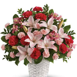 Pink lilies and red carnations in a white woven basket