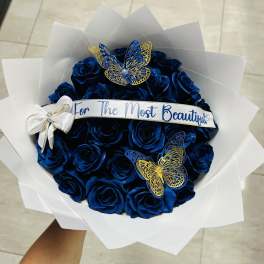 Bouquet of blue roses with butterfly decorations and a ribbon banner
