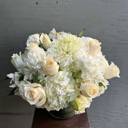 White floral bouquet with cream roses and chrysanthemums in a glass vase