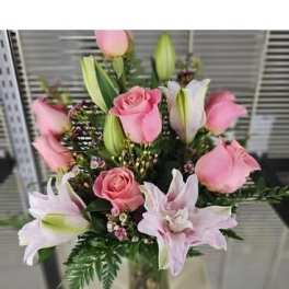 Pink roses and lilies arranged in a glass vase