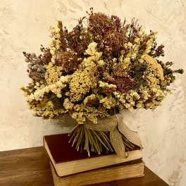 Dried flower bouquet tied with burlap ribbon, resting on stacked books