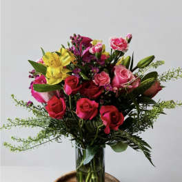 Mixed bouquet of pink and yellow flowers in a clear glass vase
