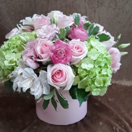 Pink roses and green hydrangeas arranged in a pale pink box