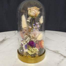 Dried flower arrangement under a glass dome with a gold base