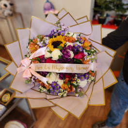 Colorful mixed bouquet with a pink ribbon and gold-edged wrap