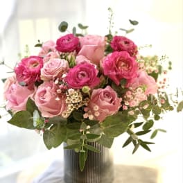 Pink roses and ranunculus in a ribbed vase