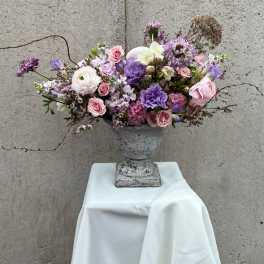 Lavender and pink floral arrangement in a gray urn vase