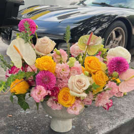 Colorful floral arrangement in a pedestal vase with roses and anthuriums