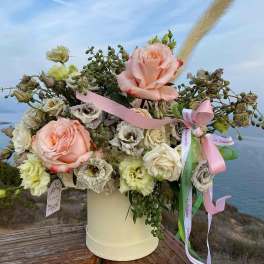 Pink and white roses arranged in a cream hatbox with ribbons