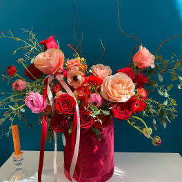 Mixed roses and ranunculus in a pink velvet box with ribbon