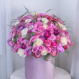 Large bouquet of pink, purple, and white roses in a lavender box