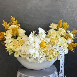 Cream and white floral arrangement with orchids and roses in a white bowl