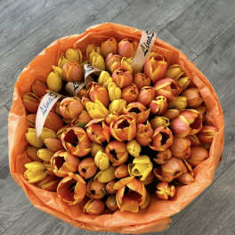 Bouquet of orange and yellow tulips wrapped in orange paper