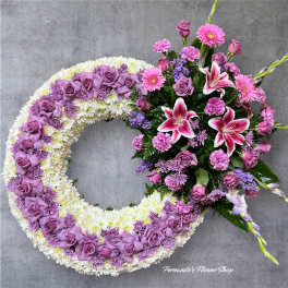 Large lavender and white wreath with a side cluster of pink lilies, roses, and carnations