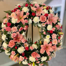 Standing wreath of pink lilies, roses, and mixed white and pink flowers on an easel