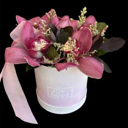 Pink orchid arrangement in a round box with a ribbon