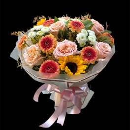 Bouquet of pink roses, sunflowers, and mixed daisies wrapped in pink ribbon