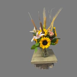 Sunflowers and lilies arranged in a clear glass vase