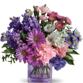 Mixed purple and pink flowers in a purple glass vase