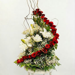 Tall arrangement of red roses and white lilies on a pedestal stand