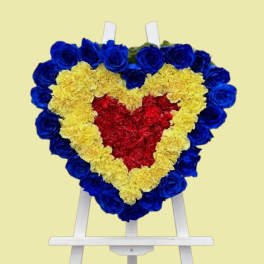 Heart-shaped floral wreath on a white easel with blue, yellow, and red flowers