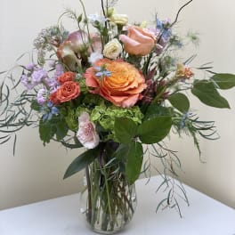 Mixed bouquet of peach and pink roses in a glass vase